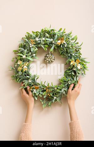 Weibliche Hände mit wunderschönem Mistelkranz an der farbigen Wand Stockfoto