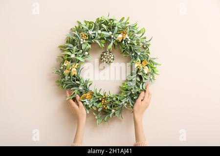 Weibliche Hände mit wunderschönem Mistelkranz an der farbigen Wand Stockfoto