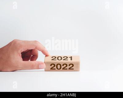 Hand hält den Holzwürfelblock mit Kalenderjahreszahlen für die Drehung von 2021 auf 2022 isoliert auf weißem Hintergrund mit Kopierraum, si Stockfoto