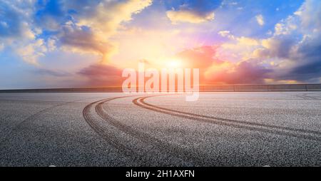 Asphalt Rennbahn Straße und Himmel Wolken bei Sonnenuntergang.Straße Boden Hintergrund. Stockfoto