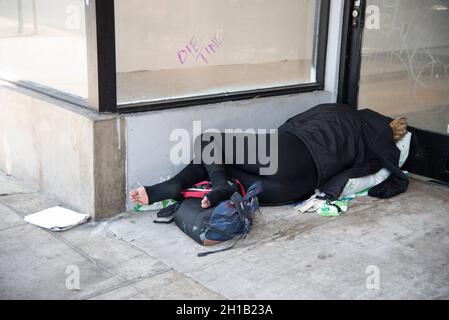 Los Angeles, CA USA - 12. Juli 2021: Obdachlose Frau schläft vor einem leeren Einzelhandelsgeschäft Stockfoto