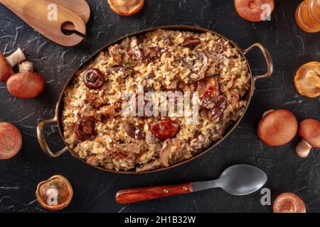 Risotto ai funghi, Pilzreis, mit Zutaten, darüber liegend flach auf schwarzem Hintergrund geschossen Stockfoto