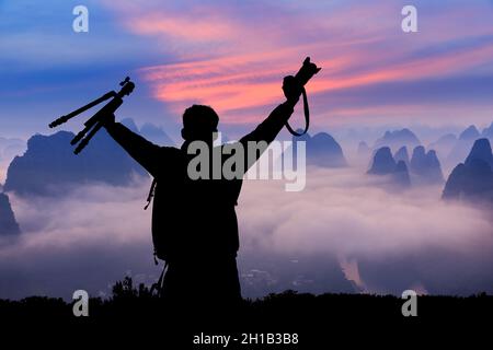 Junger Fotograf, der bei Sonnenaufgang in den Sommerbergen steht und den Blick auf die Natur genießt. Stockfoto