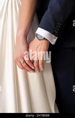 Nahaufnahme eines Brautpages, das die Hände hält. Gerade verheiratete Eheringe von Ehemann und Ehefrau aus nächster Nähe. Hochzeit und Liebe Konzept. Stockfoto