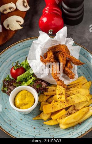 Knusprig beschichtete frittierte Hähnchenstücke mit pommes Frites und Salat Stockfoto