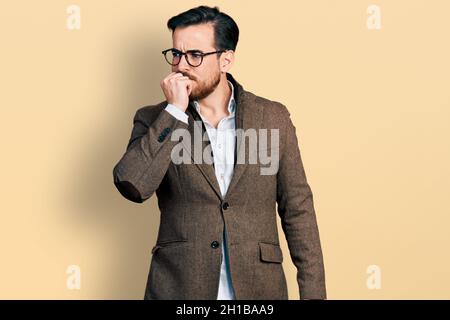 Junger hispanischer Mann trägt Business Jacke und Brille gestresst und nervös mit den Händen auf den Mund beißende Nägel. Angstproblem. Stockfoto