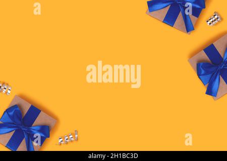 Geschenkboxen mit blauen Bändern und silbernen Konfetti auf gelbem Hintergrund. Festliches Konzept mit Copyspace. Stockfoto