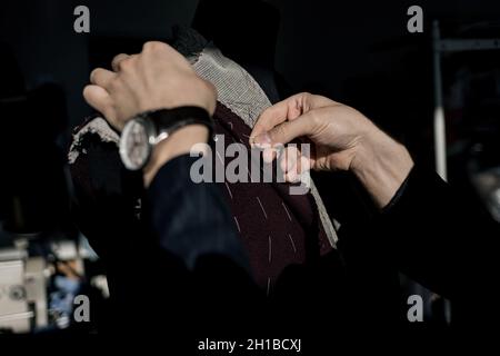 Professioneller Schneider, der Messungen für die Erstellung eines maßgeschneiderten, hochwertigen Anzugs in einem luxuriösen Schneideratelist anfertigte. Konzept der Mode, handgefertigt Stockfoto