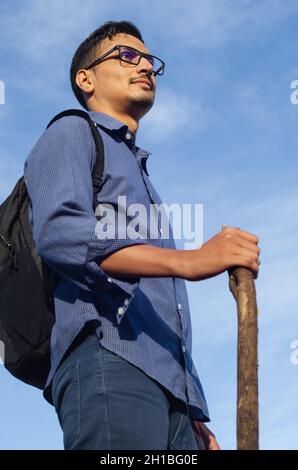 indischer Wanderer Mann hält einen Zweig als Trekkingstange. Konzept der Größe Stockfoto