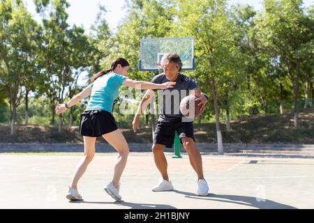Glückliches reifes Paar, das im Freien Basketball spielt Stockfoto