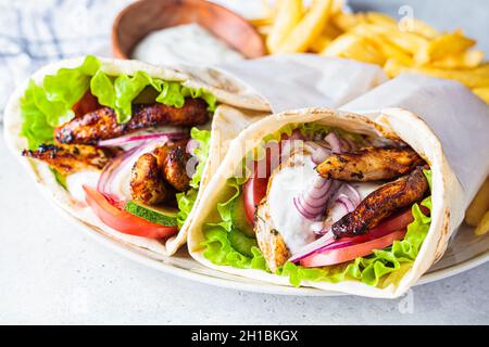 Chicken Gyros mit Gemüse, pommes frites und Tsatziki-Sauce auf einem Teller, Nahaufnahme. Griechisches Essenskonzept. Stockfoto