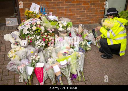Ein Polizeibeamter arrangiert Blumen und Ehrungen vor der Methodistischen Kirche von Belfairs in der Eastwood Road North, Leigh-on-Sea, Essex, wo der konservative Abgeordnete Sir David Amess starb, nachdem er am Freitag während einer Wahlkreisoperation mehrmals erstochen wurde. Bilddatum: Montag, 18. Oktober 2021. Stockfoto