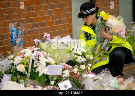 Ein Polizeibeamter arrangiert Blumen und Ehrungen vor der Methodistischen Kirche von Belfairs in der Eastwood Road North, Leigh-on-Sea, Essex, wo der konservative Abgeordnete Sir David Amess starb, nachdem er am Freitag während einer Wahlkreisoperation mehrmals erstochen wurde. Bilddatum: Montag, 18. Oktober 2021. Stockfoto