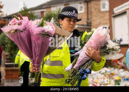 Ein Polizeibeamter arrangiert Blumen und Ehrungen vor der Methodistischen Kirche von Belfairs in der Eastwood Road North, Leigh-on-Sea, Essex, wo der konservative Abgeordnete Sir David Amess starb, nachdem er am Freitag während einer Wahlkreisoperation mehrmals erstochen wurde. Bilddatum: Montag, 18. Oktober 2021. Stockfoto