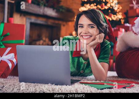 Foto von ziemlich charmante junge Frau gekleidet grünen Kostüm lächelnd Browsen moderne Gadget Schreiben Briefe drinnen Zimmer Haus Stockfoto