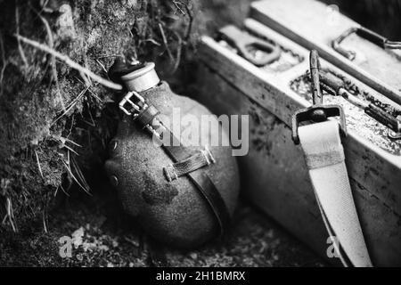 Alte deutsche Wehrmacht Zeiten des Zweiten Weltkriegs Vintage-Flasche und Schachtel mit Patronen auf dem Boden. Foto In Schwarzweiß. 2. Weltkrieg 2-mal Stockfoto