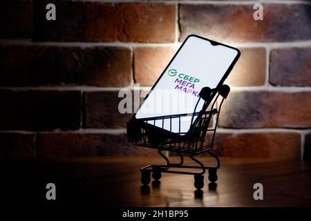 SberMegaMarket ist ein russischer Marktplatz im Besitz der Sberbank. Smartphone mit SberMegaMarket Logo auf dem Bildschirm im Warenkorb. Stockfoto