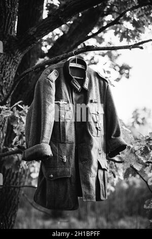 Mantel Tunika des Zweiten Weltkriegs Deutsche Wehrmacht Infanterie Soldat hängend an Einem Hanger auf Holz im Freien im Lager. 2. Weltkrieg 2-mal. Uniform Deutscher Soldaten Stockfoto