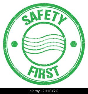 SICHERHEIT ERSTER Text auf grünem runden Briefmarkenschild geschrieben Stockfoto