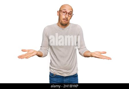 Glatze Mann mit Bart tragen lässige Kleidung und Brille ahnungslos und verwirrt Ausdruck mit Armen und Händen angehoben. Zweifel Konzept. Stockfoto