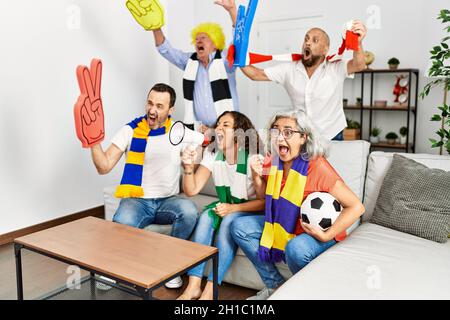 Eine Gruppe von Freunden mittleren Alters, die zu Hause Fußballspiele ansehen und unterstützen. Stockfoto