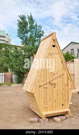 Eine hölzerne Toilette steht mitten in einer gewöhnlichen Stadtstraße Stockfoto