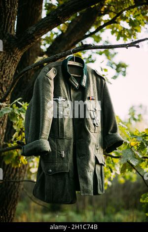 Mantel Tunika des Zweiten Weltkriegs Deutsche Wehrmacht Infanterie Soldat hängend an Einem Hanger auf Holz im Freien im Lager. 2. Weltkrieg 2-mal. Uniform Deutscher Soldaten Stockfoto