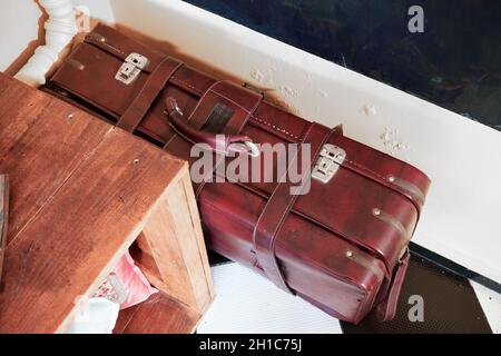 Vintage roter Koffer auf dem Boden. Reisen, Umziehen oder Verlassen des Zuhauses. Stockfoto