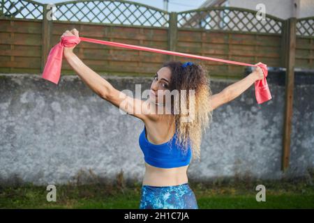 Kaukasische blonde Frau Durchführung Strecken mit elastischen Bändern, Lifestyle-Konzept, Fitness. Stockfoto