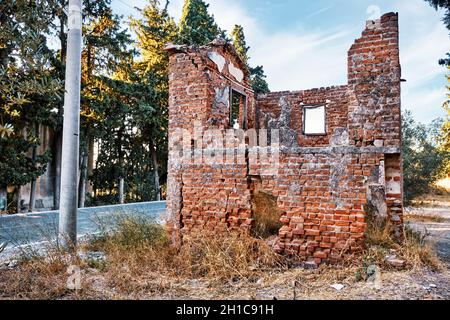 Ruinen eines verlassenen zweistöckigen Backsteinhauses, das sich außerhalb eines ländlichen Wiesenfeldes befindet. Stockfoto