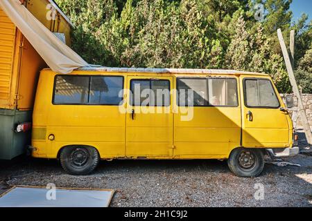 Urla, Türkei - September, 2021: Oldtimer-Minibus im gelben Retro-Stil, der auf einer gepflasterten Straße geparkt ist. Stockfoto