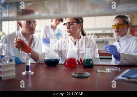 Junge Chemiestudenten konzentrieren sich auf den Umgang mit gefährlichen Chemikalien in einer Arbeitsatmosphäre im Universitätslabor. Wissenschaft, Chemie, Labor, Stockfoto