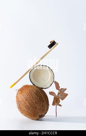 Harte Bio-Zahnbürste, Eukalyptus und Kokosnuss auf grauem Hintergrund. Natürliche organische Zahnhygiene. Stockfoto