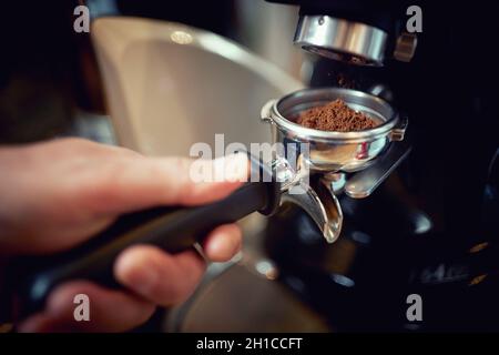 Barkeeper nimmt eine Messung von duftendem und aromatischem gemahlenem Kaffee aus dem Espresso-Gerät. Kaffee, Getränke, Bar Stockfoto