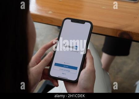 CHIANG MAI, THAILAND, OCT 10, 2021 : Eine Frau hält Apple iPhone 12 mit LinkedIn-Anwendung auf dem Bildschirm.LinkedIn ist eine Foto-Sharing-App für Stockfoto