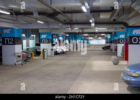 Moskau, Russland - 16. November 2020: Tiefgarage in einem großen Einkaufszentrum. Blaue Säulen mit Zahlen, Gästewagen, Einkaufswagen Stockfoto