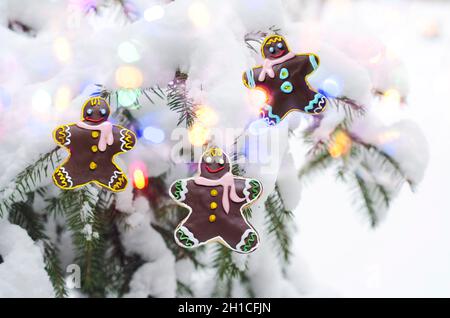 Weihnachtskonzept mit Lebkuchenmännern auf dem Hintergrund eines entkofften Weihnachtsbaums und Bokeh Stockfoto