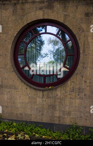 Vertikale Nahaufnahme eines runden Fensters an einer hölzernen Wand Stockfoto