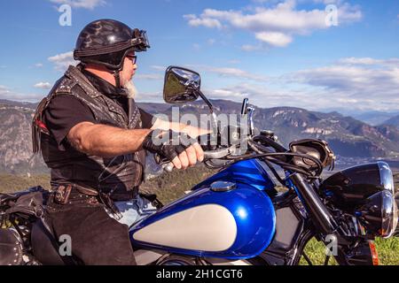 Kerl auf einem Retro-Cruiser-Motorrad auf Bergstraße in Südtirol genießen die schöne Aussicht Stockfoto