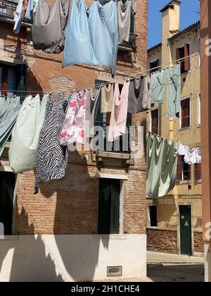 Hängende Kleidung, die auf einer kleinen traditionellen Straße in Venedig, Italien, zum Trocknen gebracht wird. Reisehintergrund Stockfoto