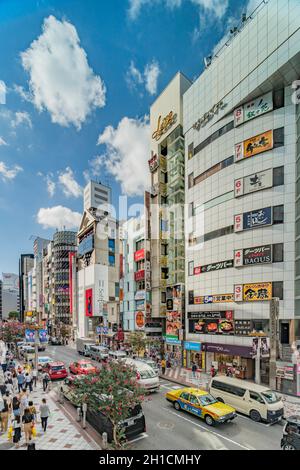 Einkaufsstraße, die zur Kreuzung Shibuya Crossing vor der Shibuya Station führt, an einem hellen, blauen Himmel. Stockfoto