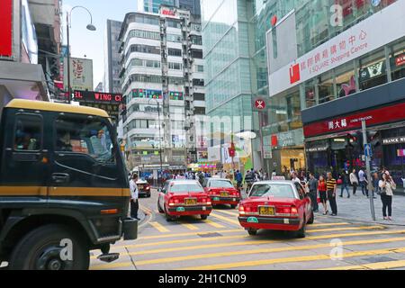 HONGKONG, CHINA - 27. APRIL 2017: Menschen überqueren die Straße und laufen in der Nähe des berühmten i Square Shopping Centers in der Nathan Road in Hongkong mit roten Zahlen herum Stockfoto