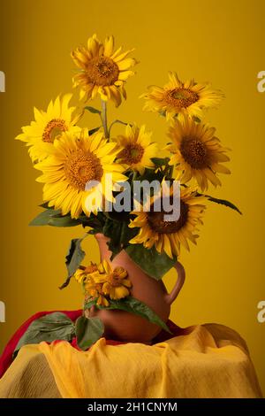 Stillleben. Wunderschöne Sonnenblumen in Keramikkrug auf gelbem Hintergrund Stockfoto
