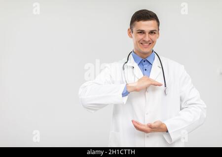 Ein lächelnder Arzt steht nach vorne und hat seine Hände angehoben, um für ein neues Produkt zu werben. Stockfoto