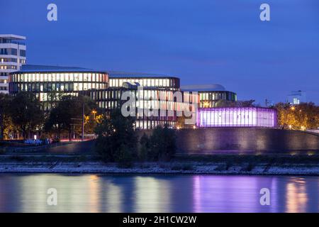 Blick über den Rhein auf das Bürogebäude der Kölner Oval-Büros und das magentafarbene Flutpumpwerk im Stadtteil Bayenthal, Col Stockfoto