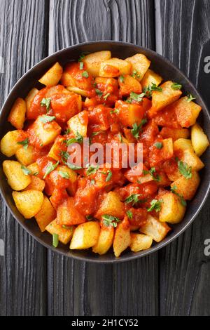 Patatas Bravas ist ein klassisches spanisches Gericht aus gebratenen Kartoffelwürfeln, serviert mit einer würzigen Dip-Sauce aus nächster Nähe auf dem Teller auf dem Tisch. Vertikale Ansicht von oben Stockfoto