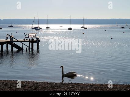 Eine malerische Aussicht auf Segelboote in der Sonne an der Bucht am Ammersee in Deutschland Stockfoto