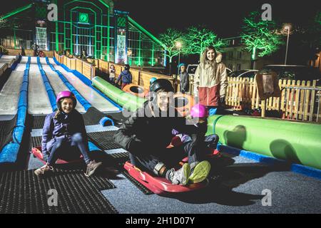 Belfort, Frankreich - 26. Dezember 2017: Kinder und Erwachsene rodeln auf einer Eisrutsche, die bei der Weihnachtsfeier in der Innenstadt installiert wurde Stockfoto