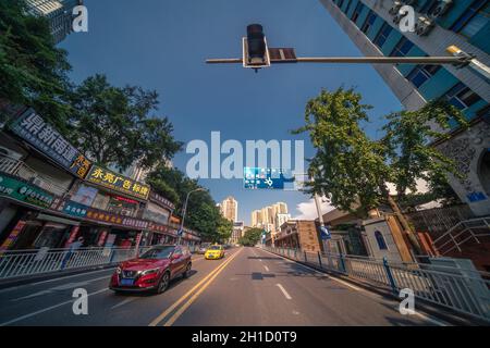 Chongqing, China - August 2019: Taxis und Autos fahren auf belebten Straßen der Stadt Chongqing unter den modernen Handels- und Geschäftsgebäuden in Ji Stockfoto