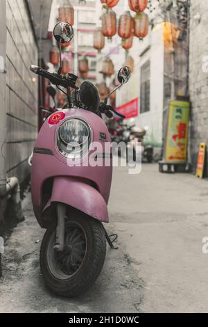 Feng Huang, China - August 2019: Kleiner rosafarbener Roller, der in der engen Straßendurchfahrt in der Feng Huang Altstadt, Provinz Hunan, geparkt ist Stockfoto